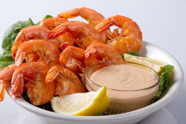 A platter of shrimp served with lemon and dipping sauce